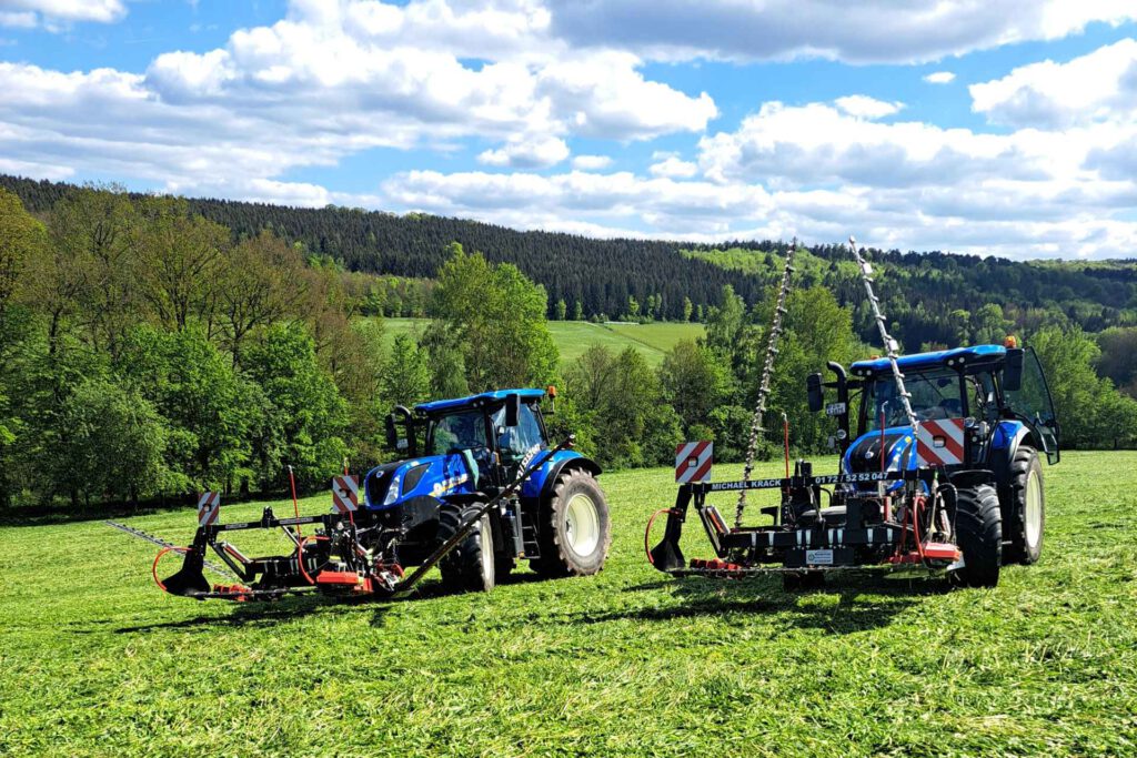 New Holland bei der Mahd auf einer grüner Wiese im Sonnenuntergang