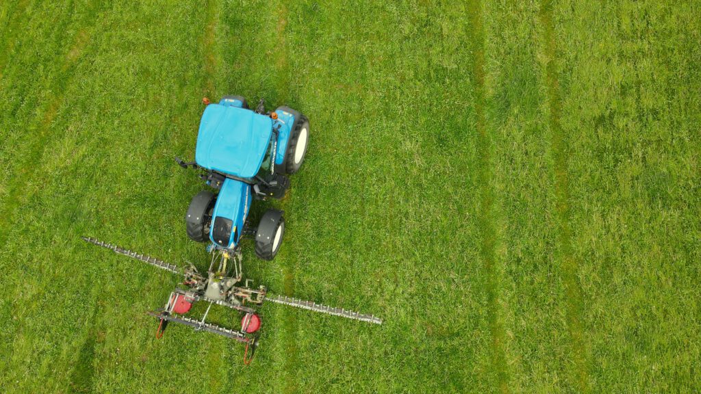 New Holland bei der Mahd auf einer grüner Wiese
