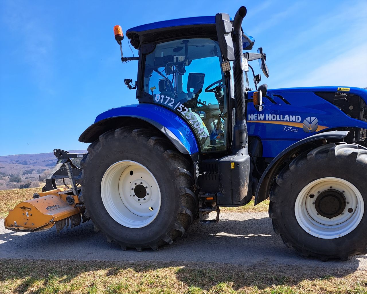 New Holland Traktor zieht eine Maschine zum Mulchen